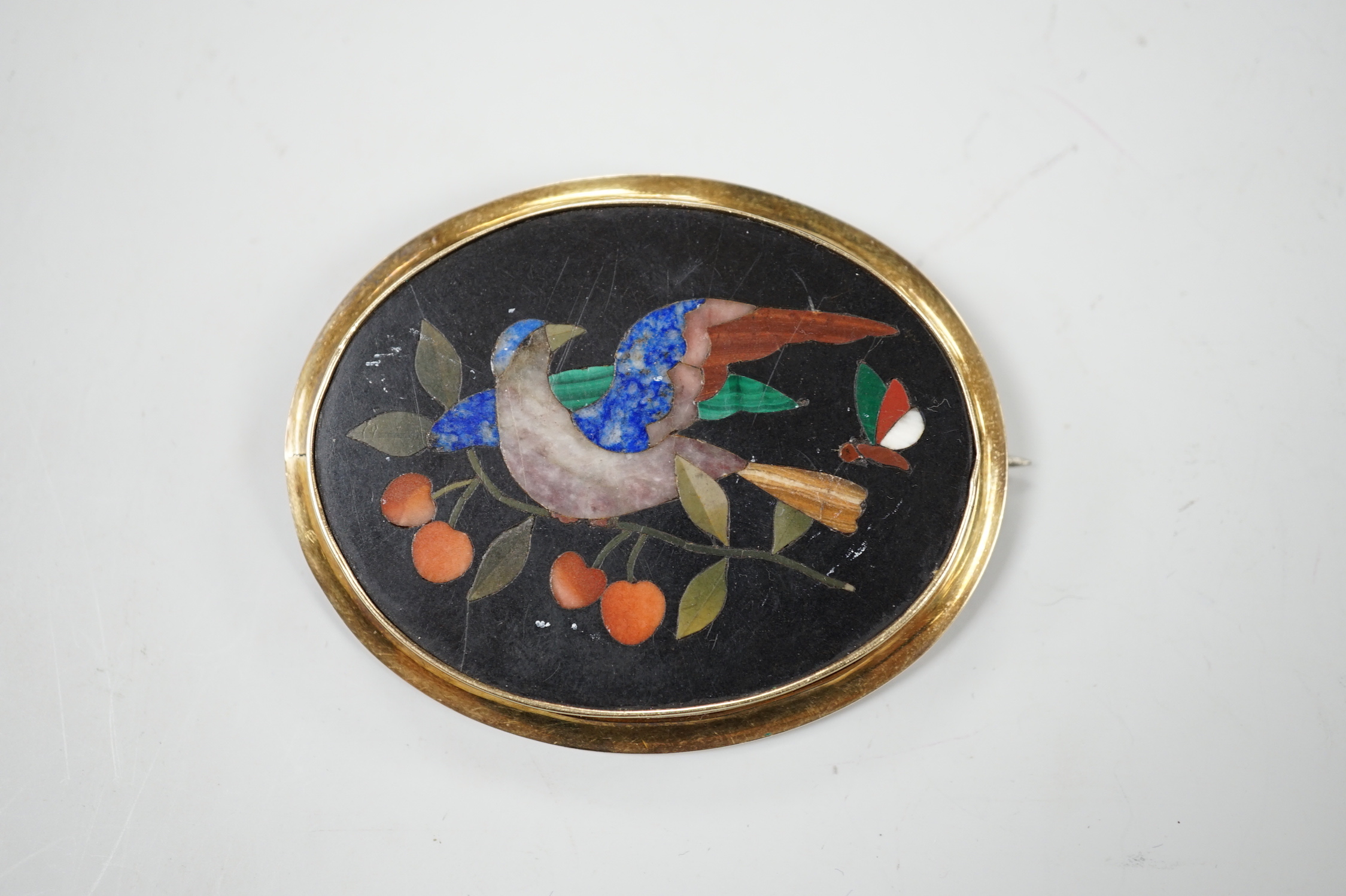 A Victorian yellow metal mounted pietra dura set oval brooch, depicting a bird and butterfly, 63mm.